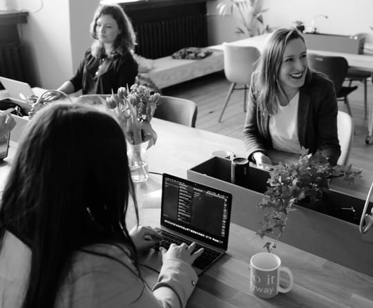 three women on their laptos and phones